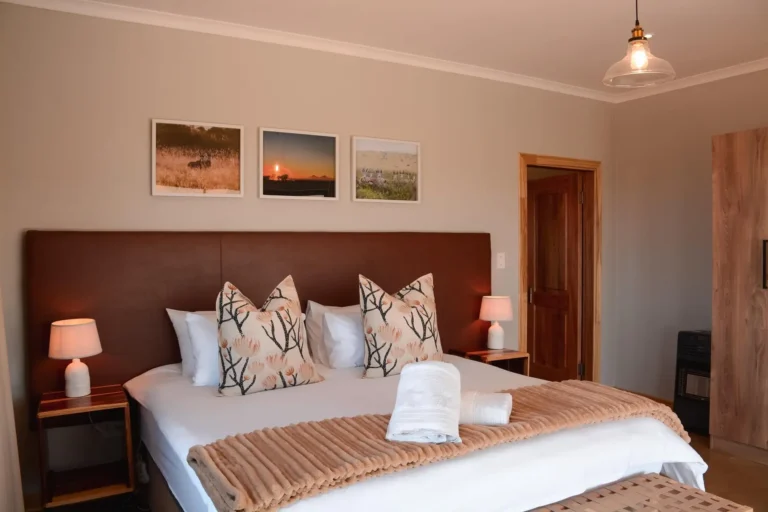 Schlafzimmer der Safari-Lodge mit Doppelbett und Wildtierfotos