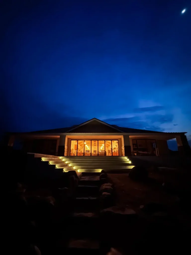 Beleuchtete Safari-Lodge bei Nacht unter blauem Abendhimmel