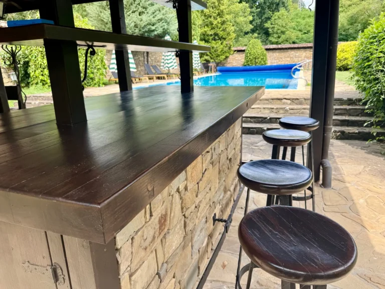Außenbar aus Naturstein mit Barhockern und Blick auf den Pool des Jagdhauses in Bulgarien