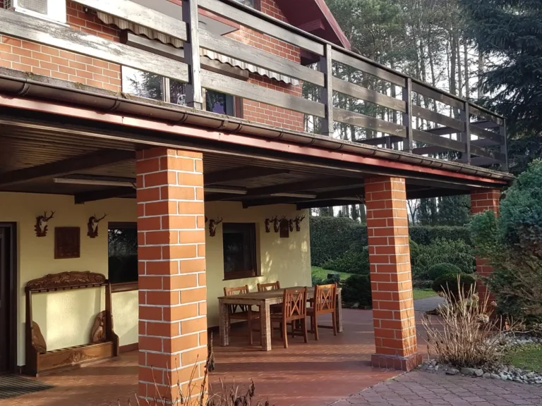 Jagdhaus mit Backsteinsäulen, Terrasse und Balkon im Wald