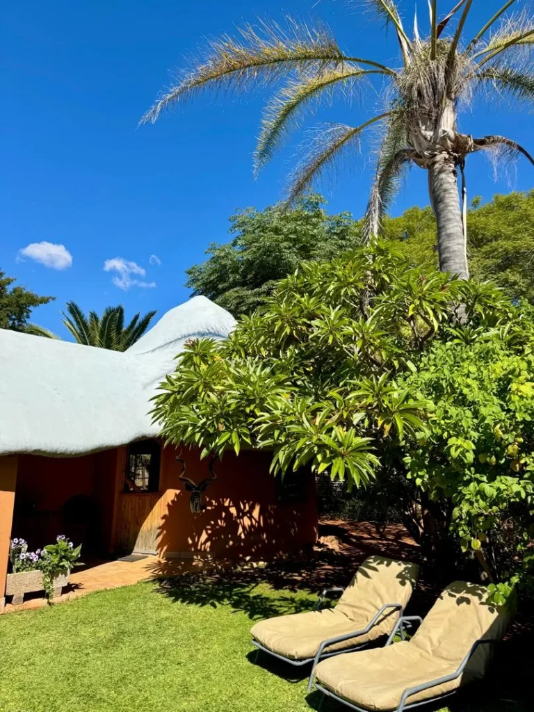 Gästehaus mit Strohdach, Sonnenliegen und Kudu-Trophäe an der Wand, Namibia