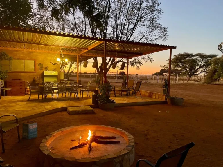 Lagerfeuer und überdachte Veranda in der Abenddämmerung auf der Jagdfarm, Namibia