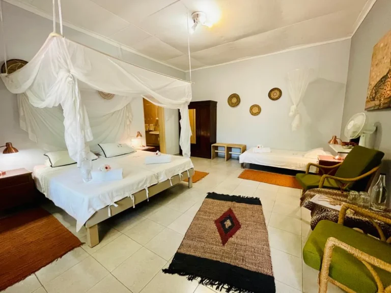 Gästezimmer mit Doppelbett, Einzelbett und Moskitonetz auf der Jagdfarm in Namibia