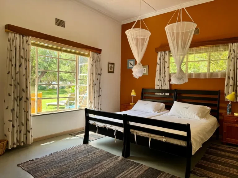 Helles Zweibettzimmer mit Blick in den Garten auf der Jagdfarm in Namibia
